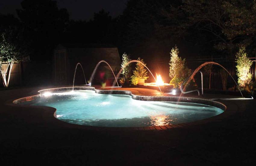 Illuminated backyard swimming pool beneath a Florida evening sky